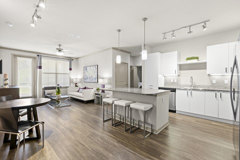 A modern kitchen with white cabinets and a wooden floor.