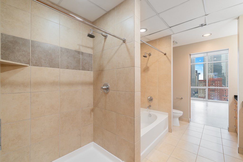 A bathroom with a shower, tub, and toilet.