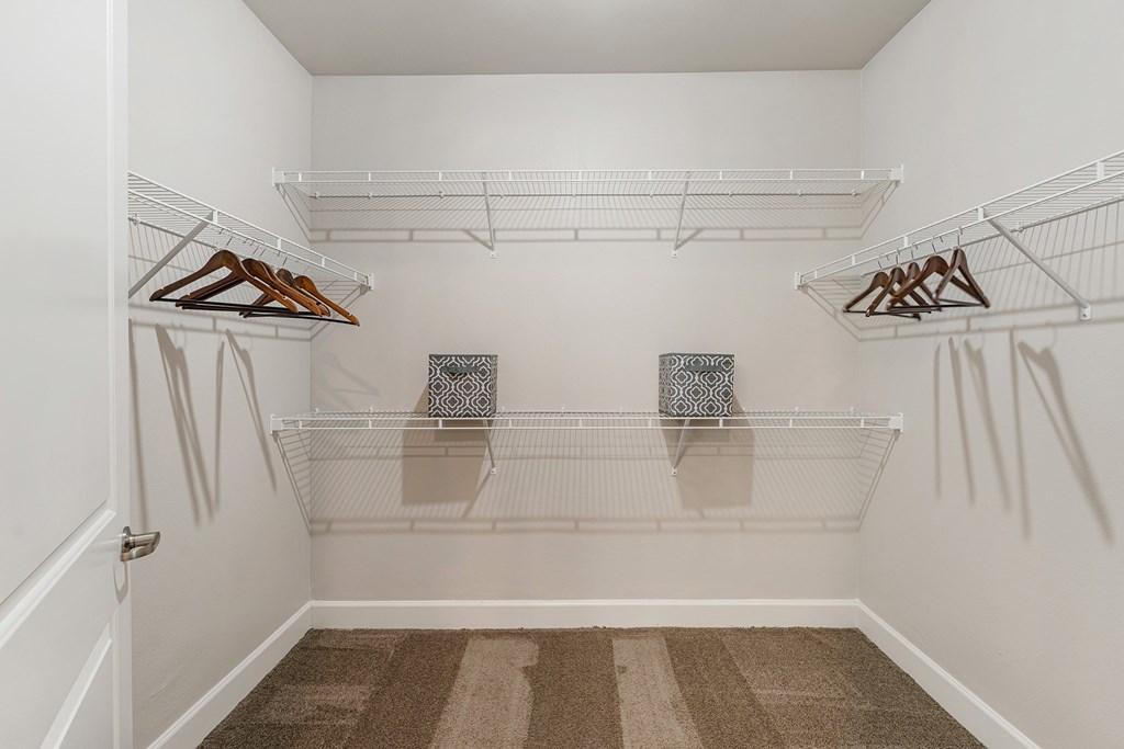 A white closet with two shelves and two hangers.