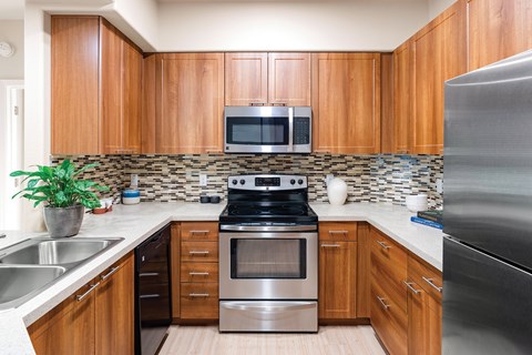 A kitchen with wooden cabinets and a stainless steel refrigerator.