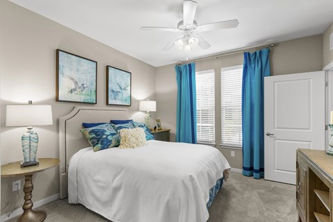 A bedroom with a white bed and blue curtains.