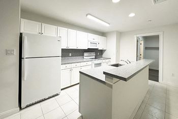 a large kitchen with white cabinets and a refrigerator
