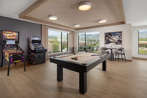 A room with a pool table, a chair, and a picture of a building on the wall.