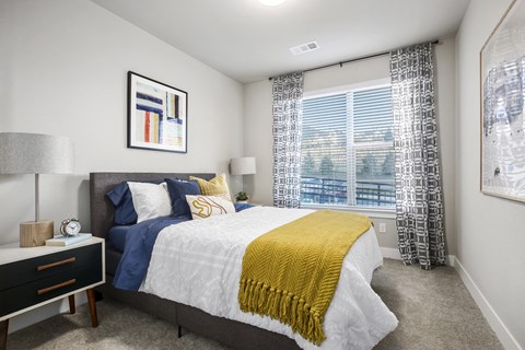 A bedroom with a bed, nightstand, and window.