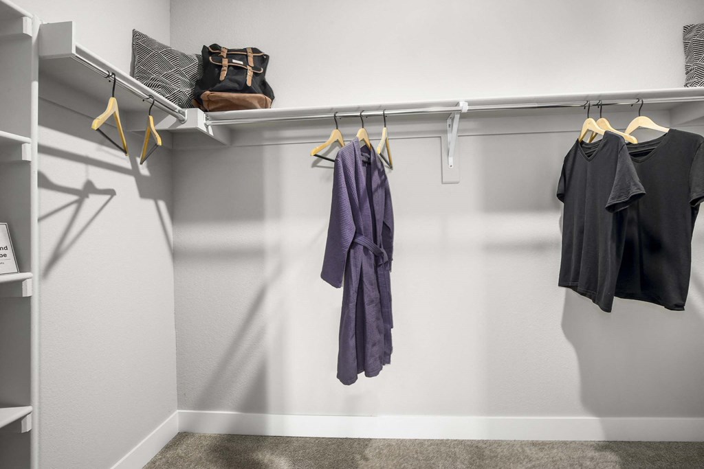 a walk in closet with robes and clothes hanging on a rack