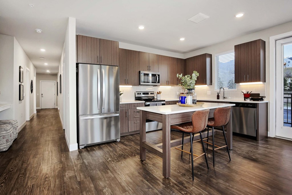 a kitchen with a large island and a stainless steel refrigerator