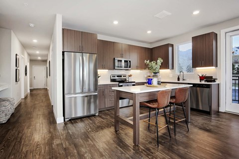 a kitchen with a large island and a stainless steel refrigerator