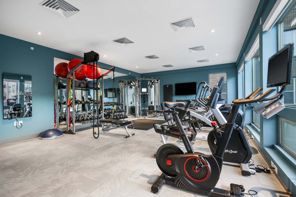 a gym with weights and cardio equipment in a room with windows