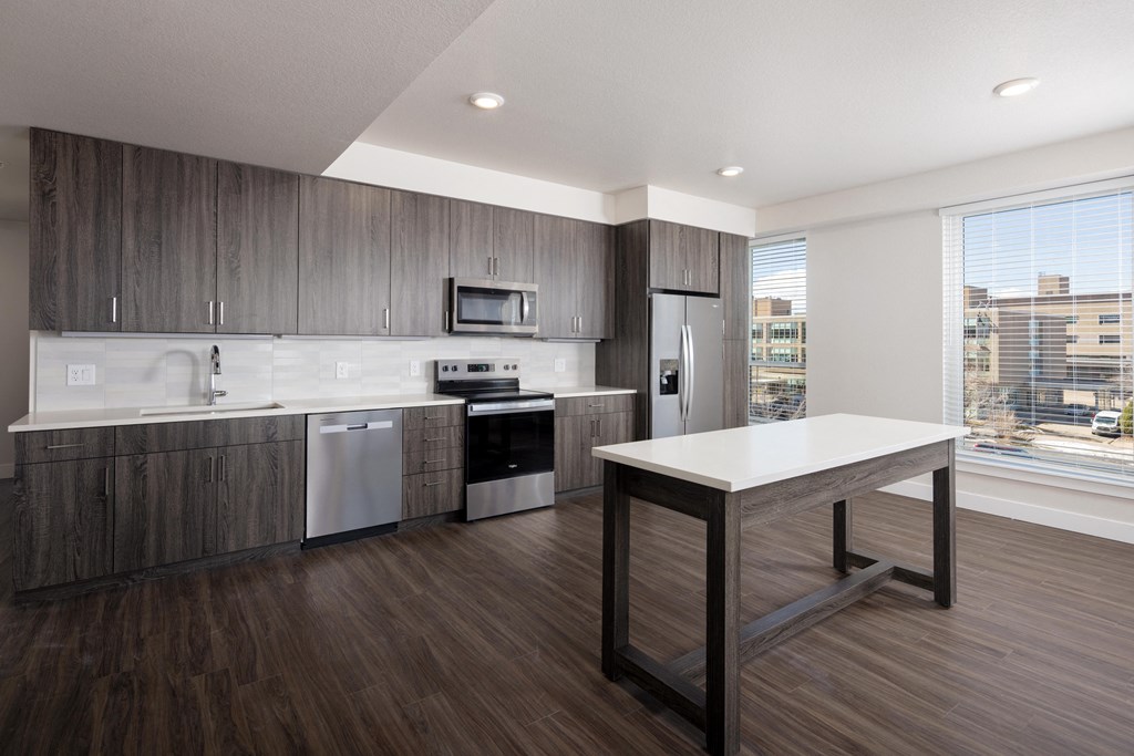A modern kitchen with dark wood floors and a white countertop.