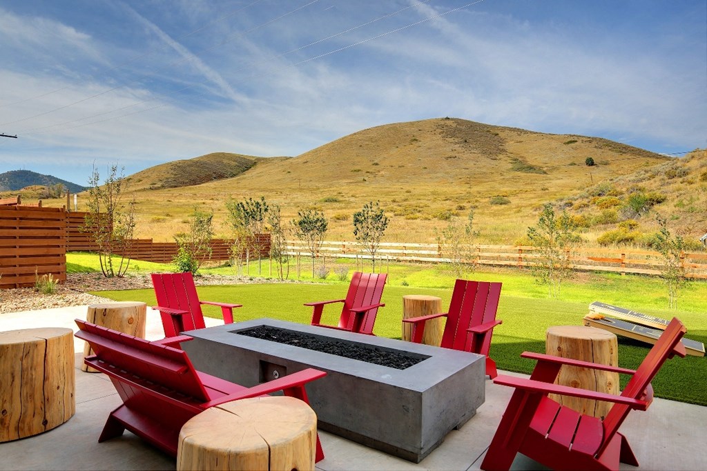 a patio with a fire pit and chairs with a mountain in the background