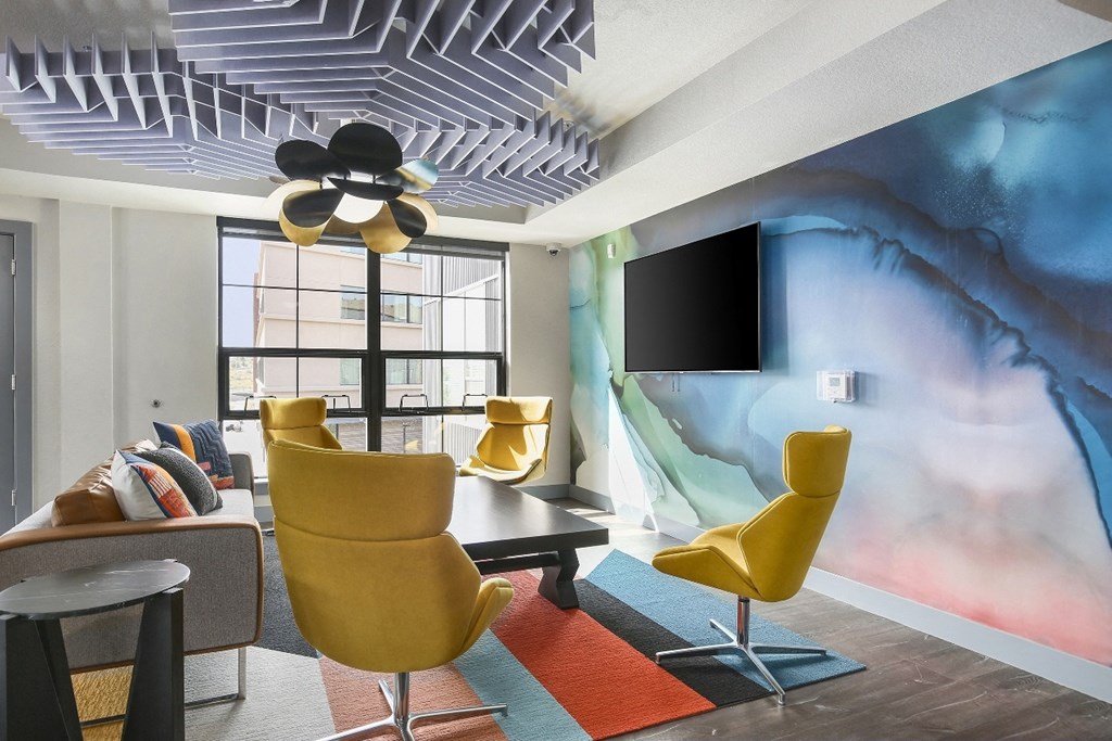 a living room with yellow chairs and a wall mural