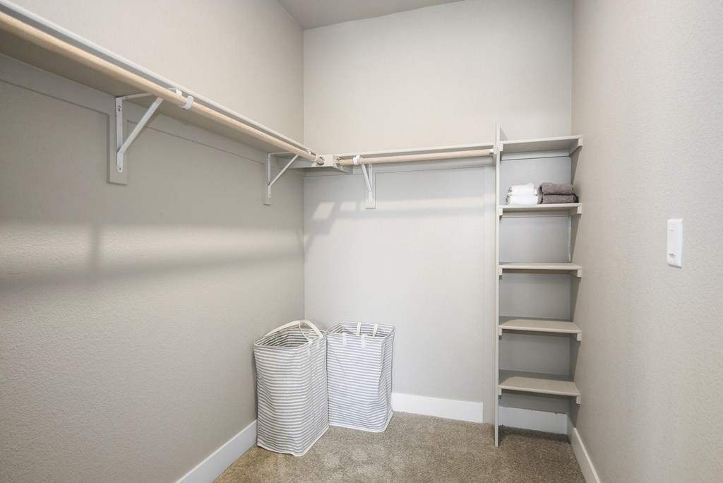 a walk in closet with white baskets and a shelving unit