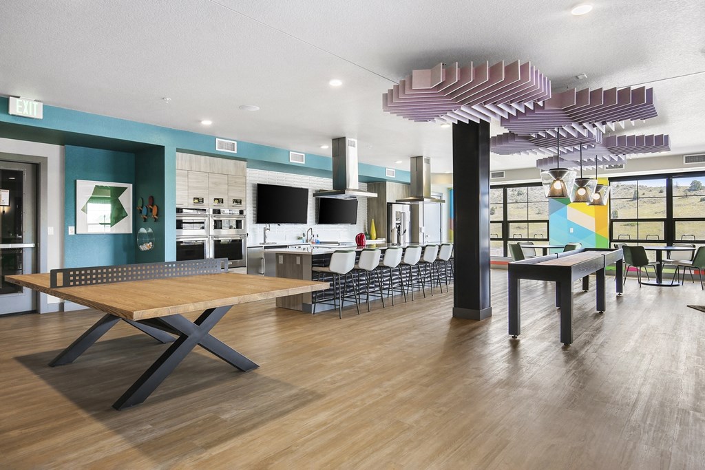 a communal room with tables and chairs and a kitchen and television