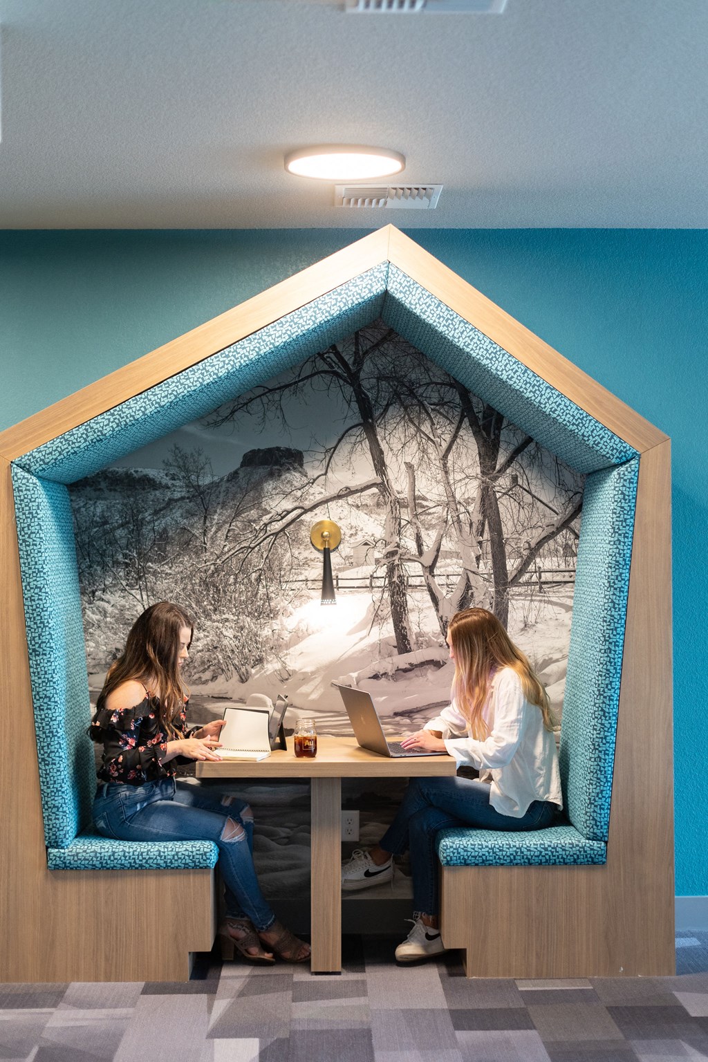 a picture of two women sitting at a table with laptops