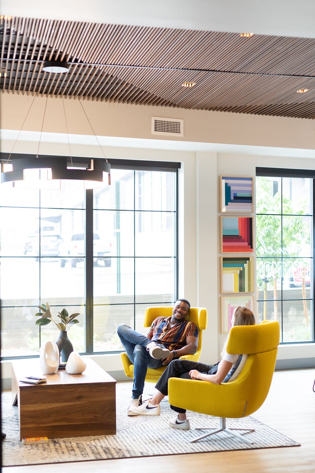 people sitting in yellow chairs in a room with large windows