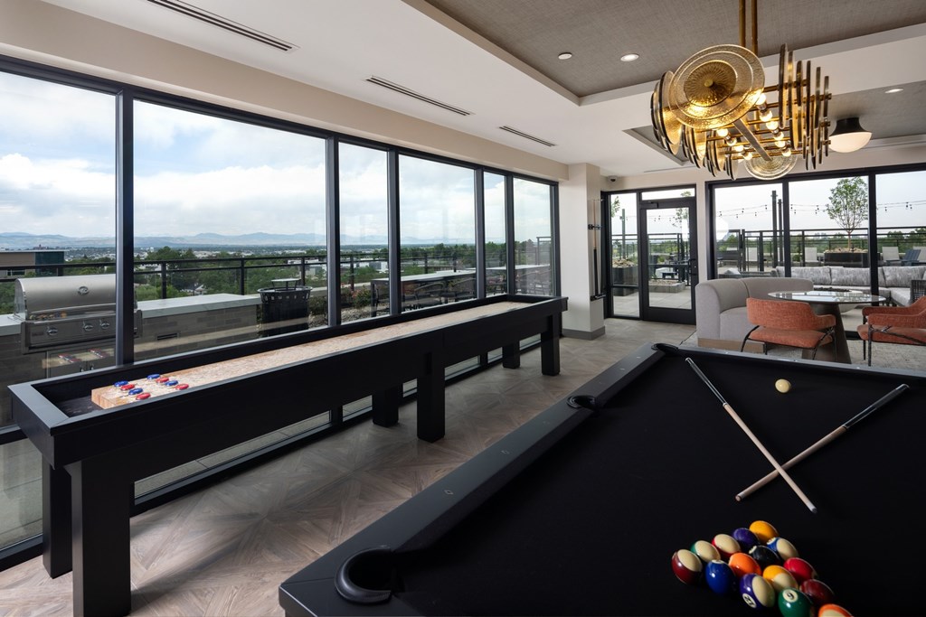 A pool table with a view of the outside through the windows.