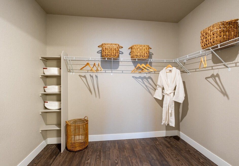 a walk in closet with a white robe and wicker baskets