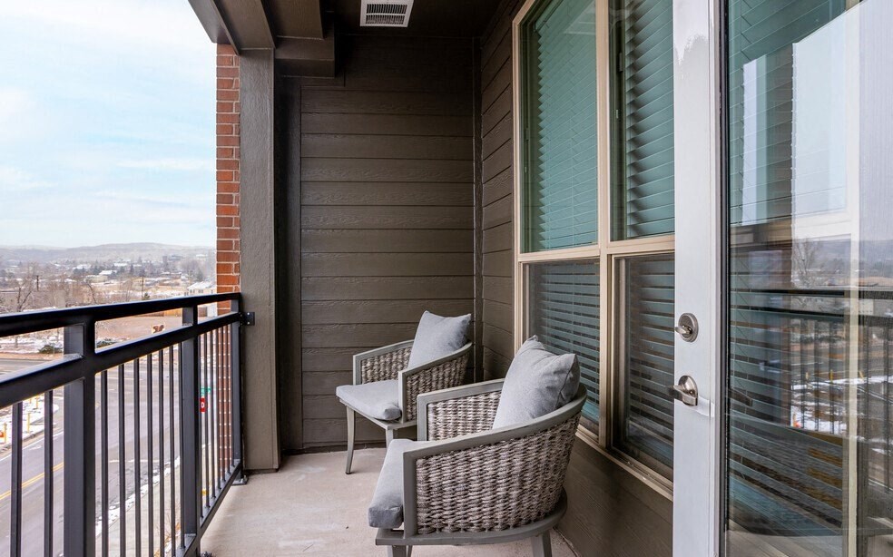 a balcony with two wicker chairs and a view of the city
