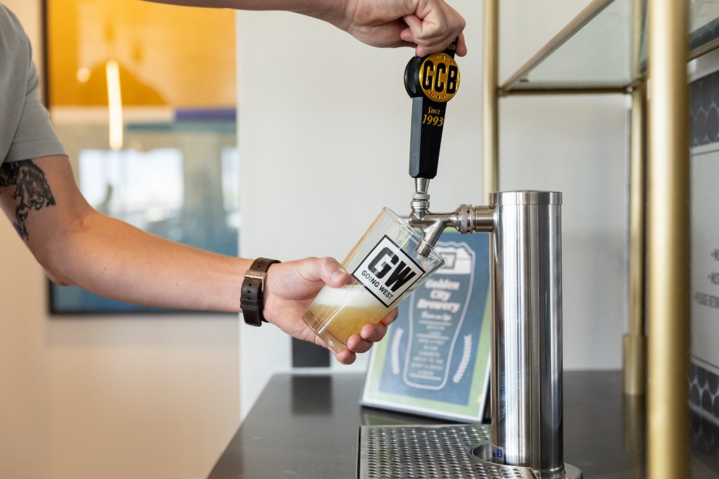 a person pouring a bottle of beer into a beer dispenser