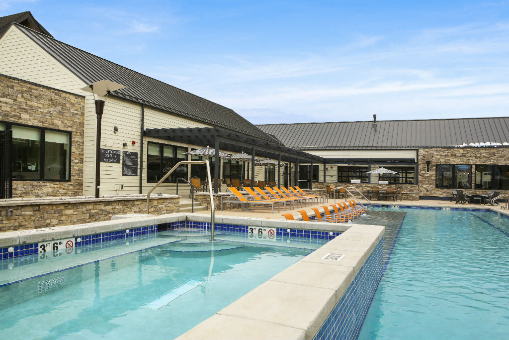 a swimming pool in front of a building with orange chairs
