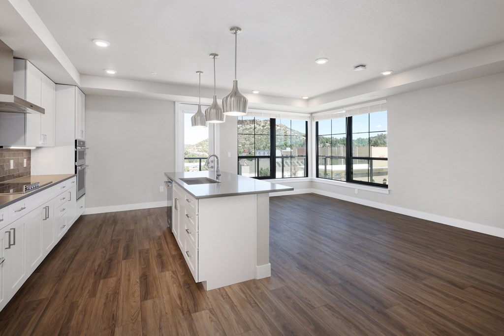 A modern kitchen with wooden floors and white cabinets.