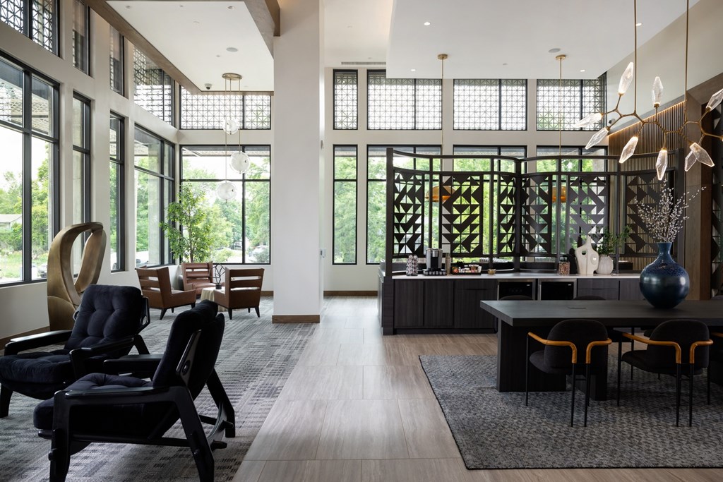 A modern living room with black chairs and a large sculpture.