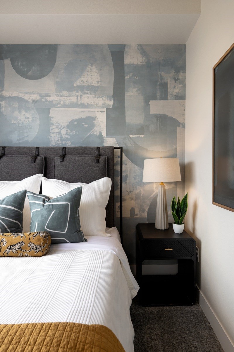 A bedroom with a bed, nightstand, and a wall mural.