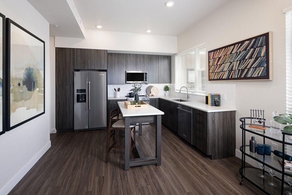 A modern kitchen with dark wood floors and a white island.