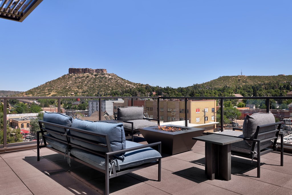 A patio with a table and chairs overlooking a mountain.