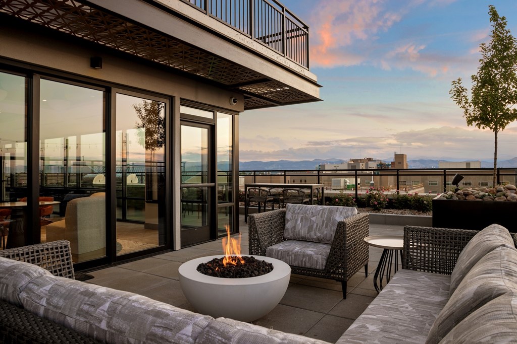 A patio with a fire pit and chairs overlooking a body of water.