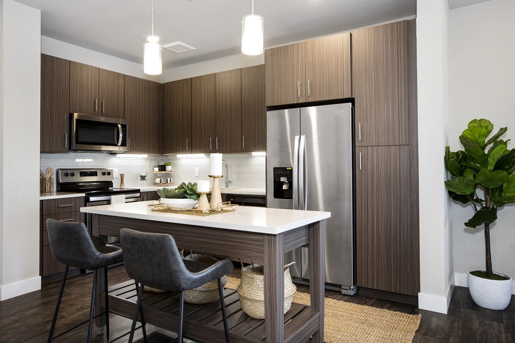 a kitchen with a large island and stainless steel refrigerator