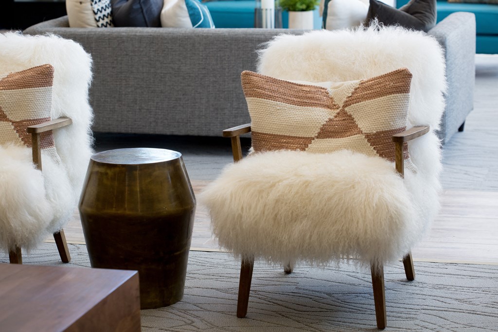a living room with two white furry chairs and a couch