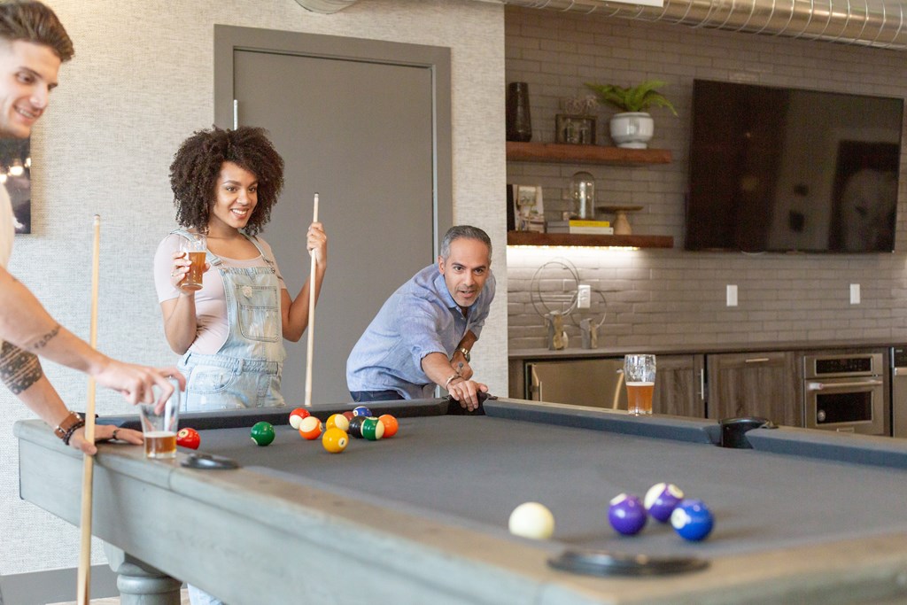 Three people playing pool in a room.