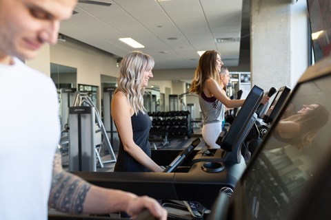three people on a treadmill in a gym