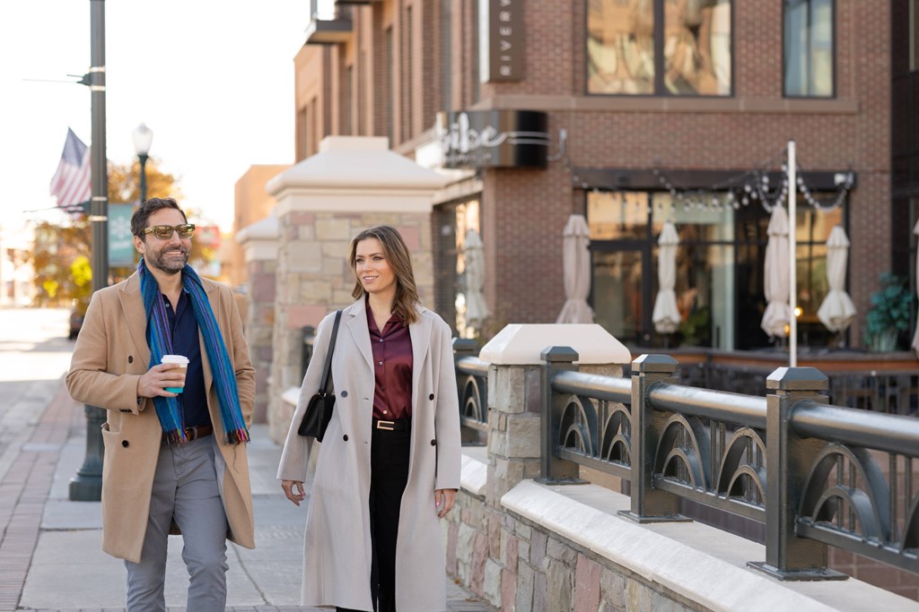 Two people walking on a sidewalk.