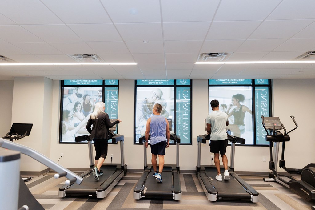 Three people are exercising on treadmills in a gym.