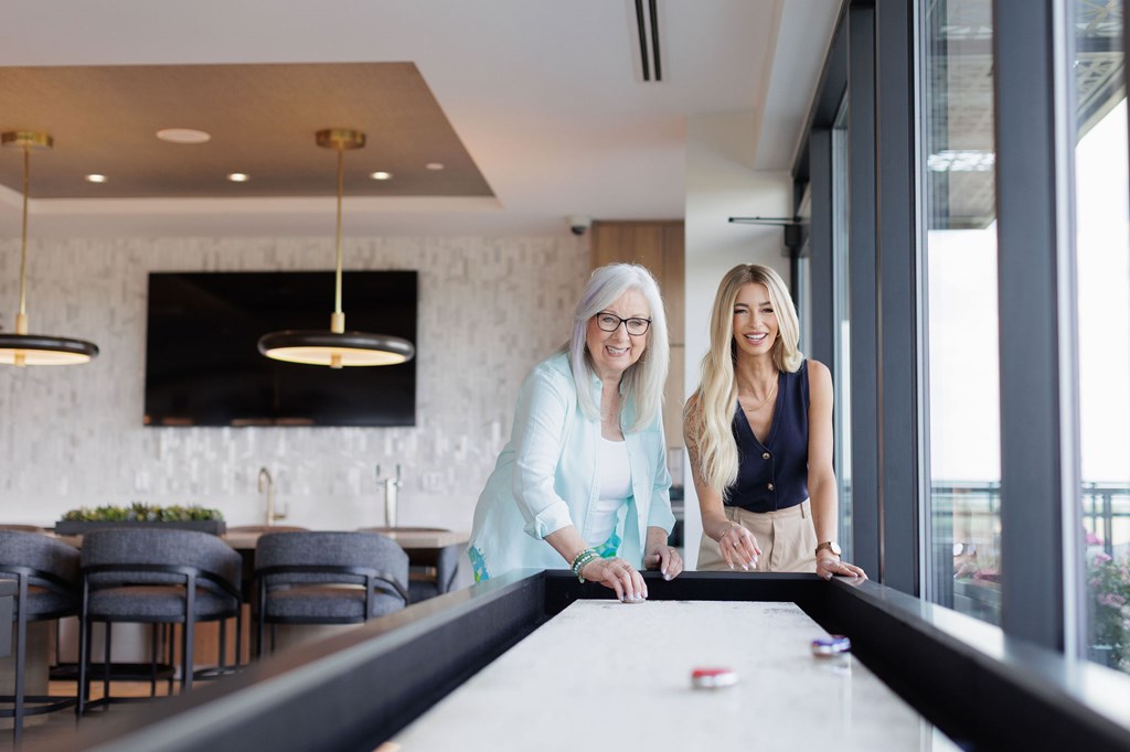 Two women playing pool in a brightly lit room.