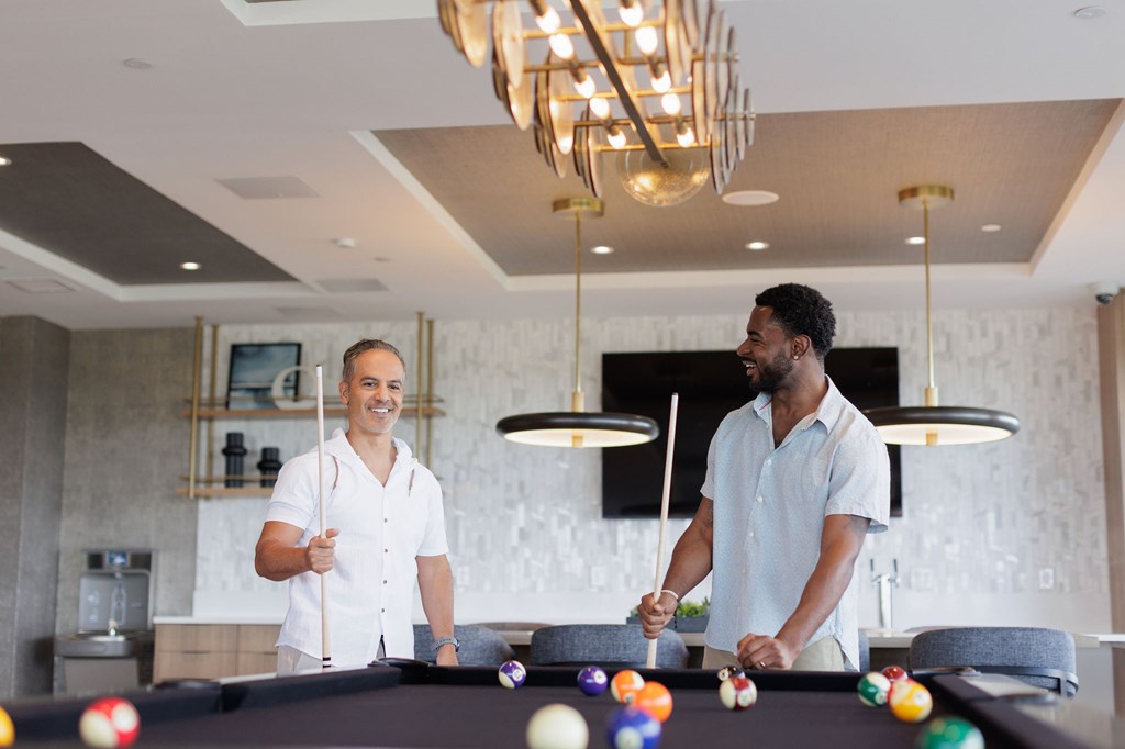 Two men playing pool in a well-lit room.