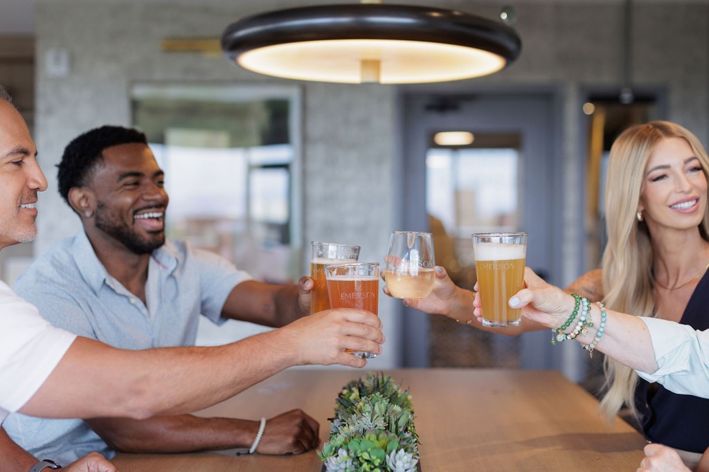 Three people toasting with beer glasses in a restaurant.