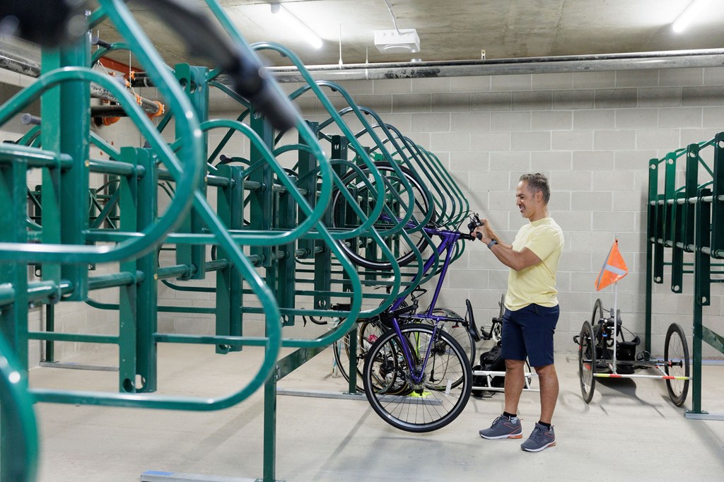 A man in a yellow shirt is standing in a bike storage area.