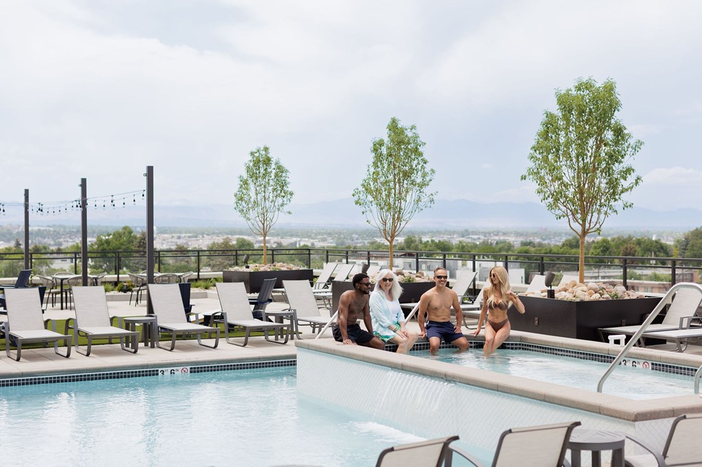 A group of people are sitting by a pool on a sunny day.