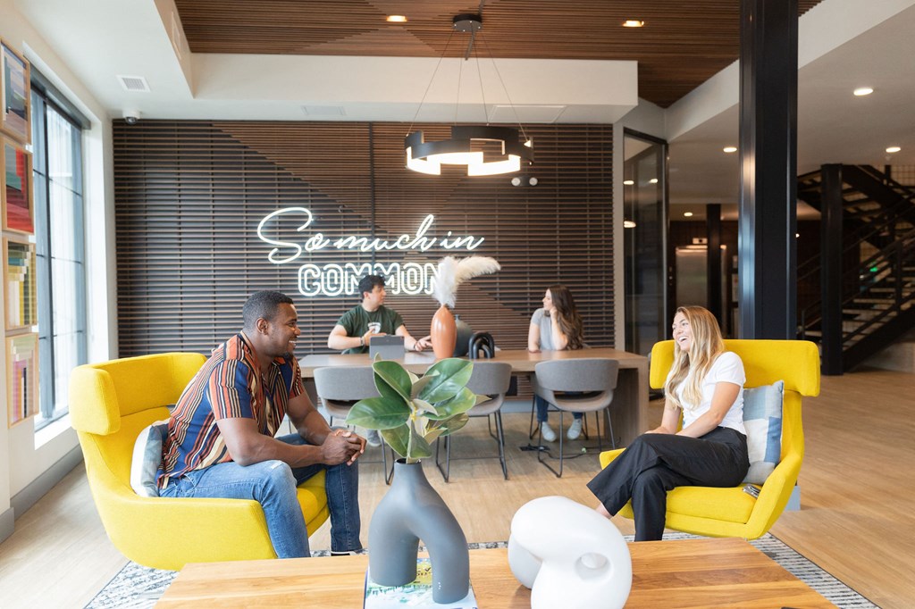 people sitting in yellow chairs in a room with a large sign on the wall