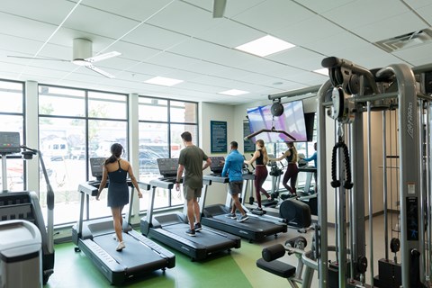 A gym with people exercising and various equipment.