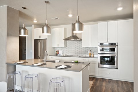 a kitchen with white cabinets and a large island with stools