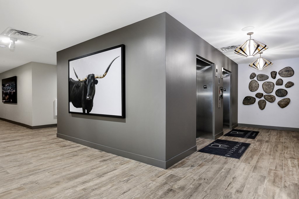 a hallway with two elevators and a picture of a bull