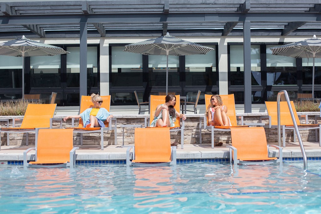 People relaxing on sun loungers by a pool.