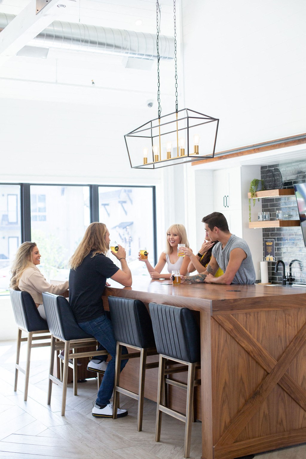 Four people are sitting at a bar with a man standing behind it.
