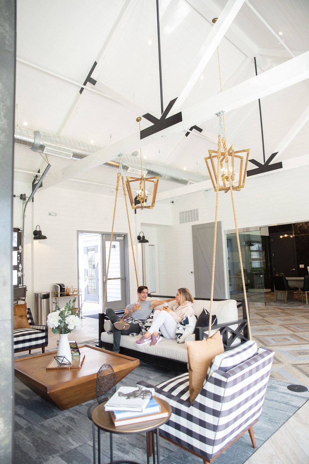 A woman is sitting on a couch in a room with a wooden coffee table and striped armchair.