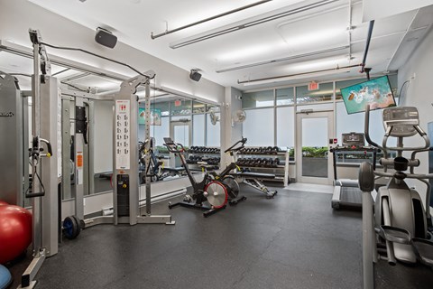 a gym with weights and cardio equipment on the floor and windows