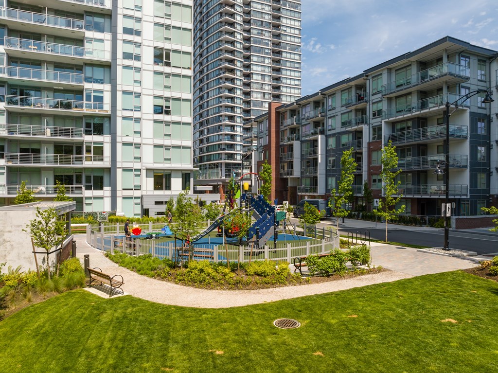 A playground with a blue slide is surrounded by apartment buildings.